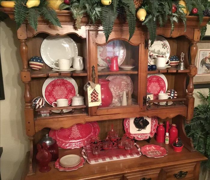 a wooden china cabinet with dishes and decor