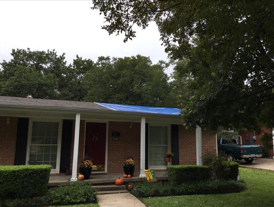 a blue tarp covers a portion of a roof on a home