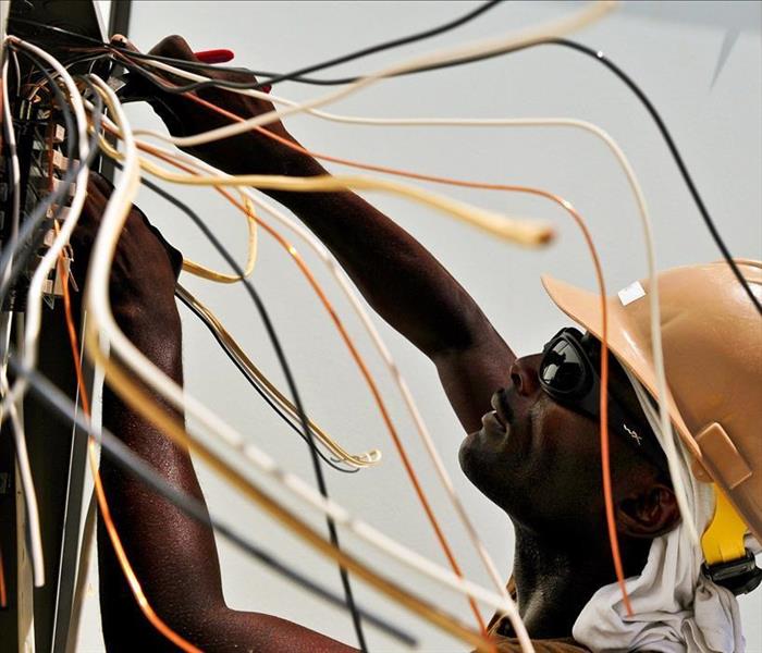 A man in a work helmet working with wires