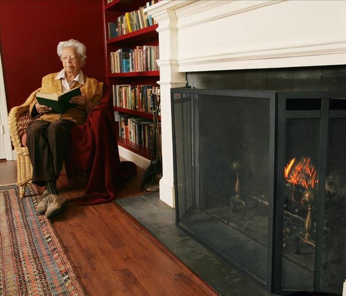 Older adult woman reading by a screened fireplace