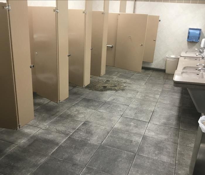 public bathroom with a murky puddle on the tile floor